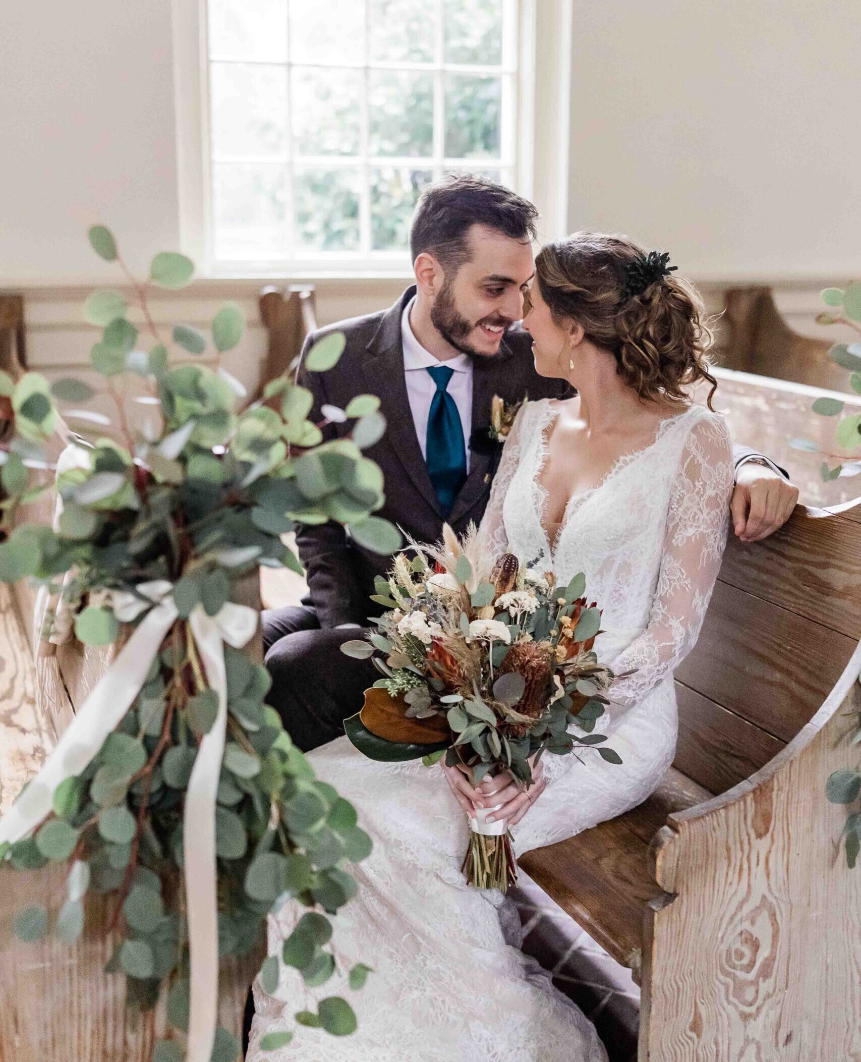 a bride and groom sitting on a bench together.