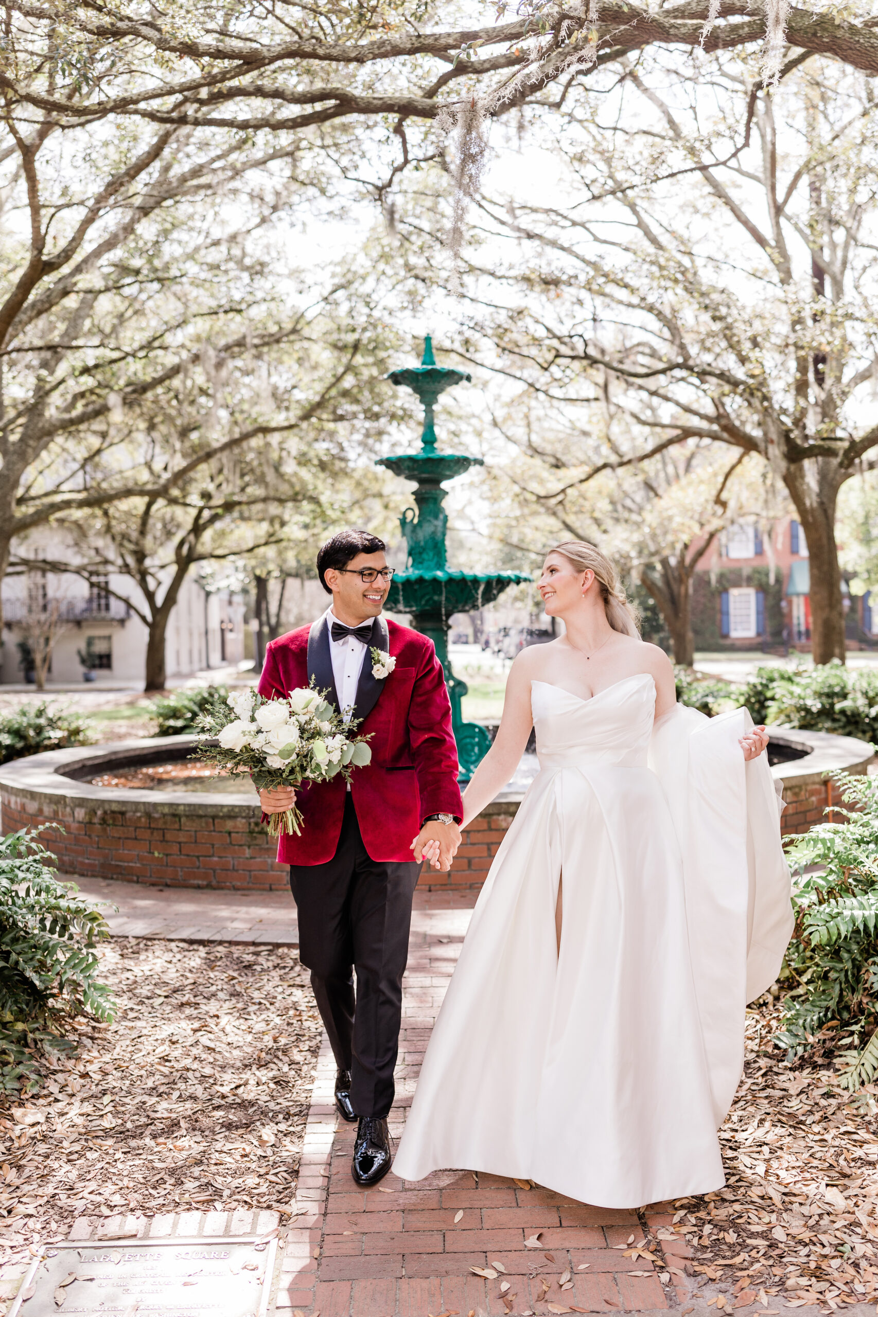 Bride and groom walking in front of lafayette square fountain