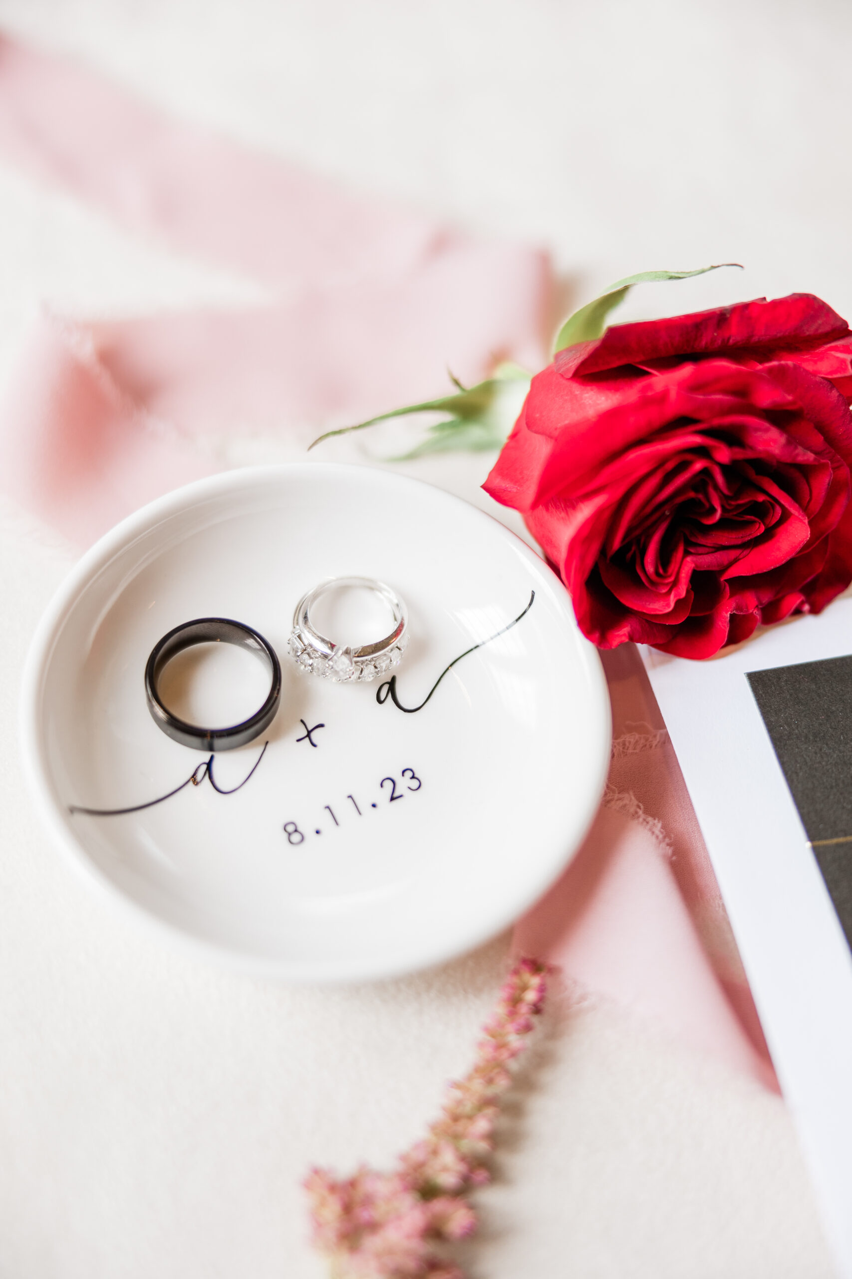 Wedding rings on a plate next to a red rose.