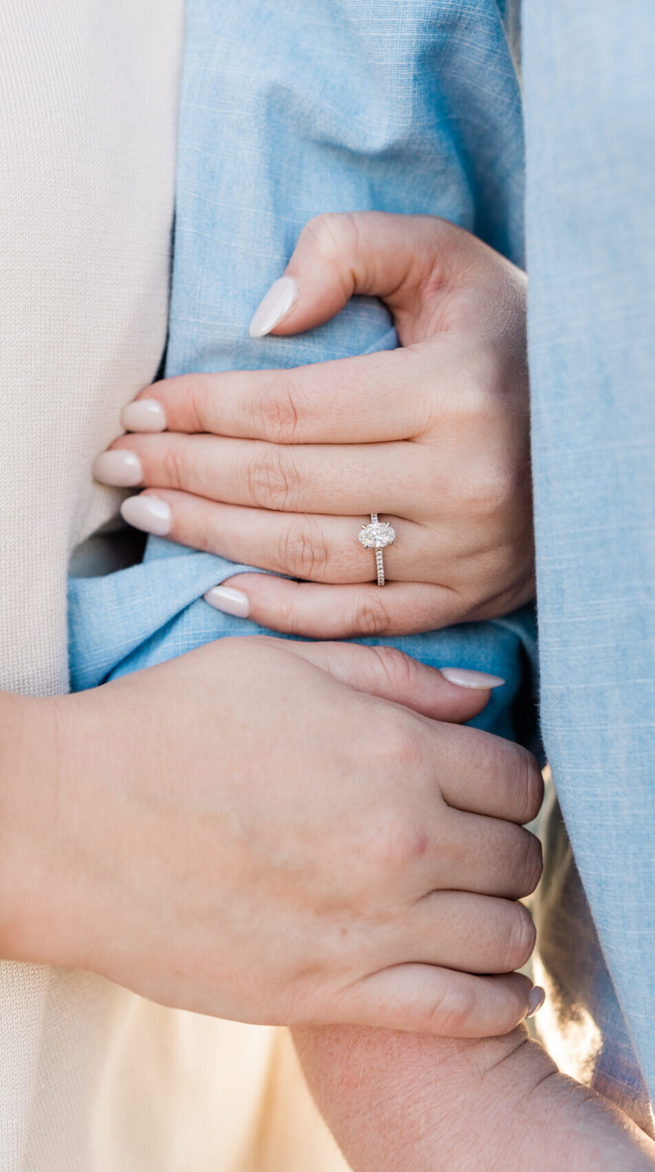 A couple holding hands in a field during an engagement session.